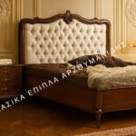 Κλασική Κρεβατοκάμαρα ALEXANDRA με καφέ πλαίσιο, ανοιχτόχρωμο καπιτονέ κεφαλάρι και έντονα διακοσμημένη καμπύλη κορυφή.