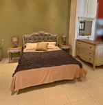 Κλασική Κρεβατοκάμαρα DUBLIN με ανοιχτόχρωμο διακοσμημένο πλαίσιο, γκρι καπιτονέ κεφαλάρι, συρταριέρα και κομοδίνα.