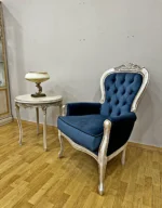 Κλασική πολυθρόνα Dublin – μπλε οβάλ καπιτονέ πλάτη, μπλε κάθισμα και ανοιχτόχρωμο διακοσμημένο πλαίσιο, δίπλα σε τραπεζάκι
